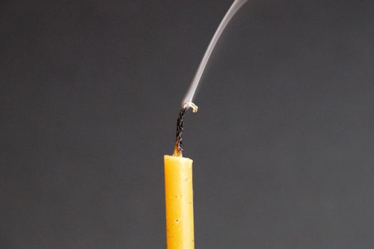 extinguished smoking wax candle on gray background close-up