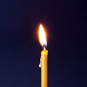 burning wax candle close-up on dark background, square photo