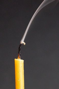 extinguished smoking wax candle on gray background close-up