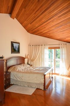 Beautiful bedroom with wooden ceiling and sun light coming through glass door