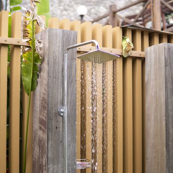 Water falling from the rain shower head of a swimming pool open area showers.