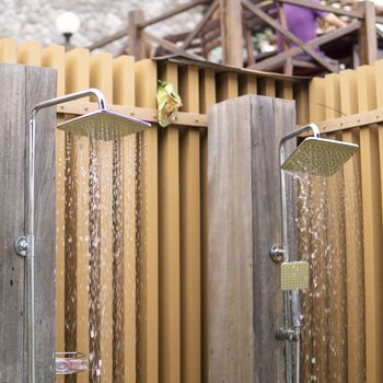 Water falling from the rain shower head of a swimming pool open area showers.