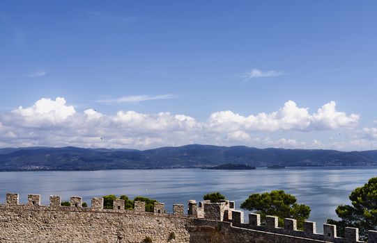  Lake Trasimeno -Italy - view from the Fortress of the Lion in Castiglione del Lago  with isola maggiore and isola minore in the background  ,beautiful crenellated walls in the foreground
