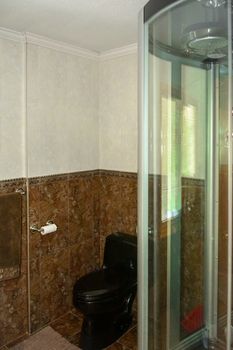 Automated shower cabin and black toilet in a bathroom of luxury house