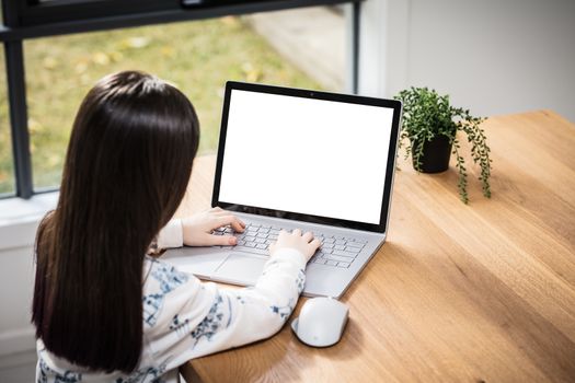 A young female child uses a computer in remote learning for her school work