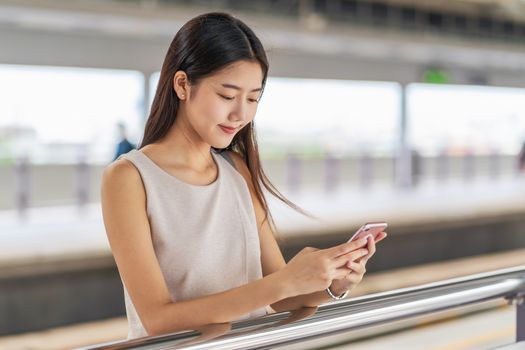 Young Asian woman passenger using social network via smart mobile phone in subway train when traveling in big city,japanese,chinese,Korean lifestyle and daily life, commuter and transportation concept