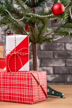 Decorated Christmas tree with wrapped beautiful red and white gifts at home with black brick wall, festive design concept, close up.