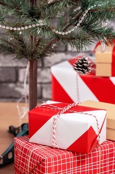 Decorated Christmas tree with wrapped beautiful red and white gifts at home with black brick wall, festive design concept, close up.