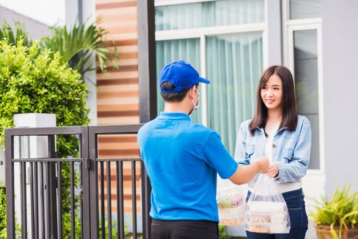 Asian young delivery man wear face mask he making grocery service giving rice food boxes plastic bags to woman customer receiving door at house after pandemic coronavirus, Back to new normal concept