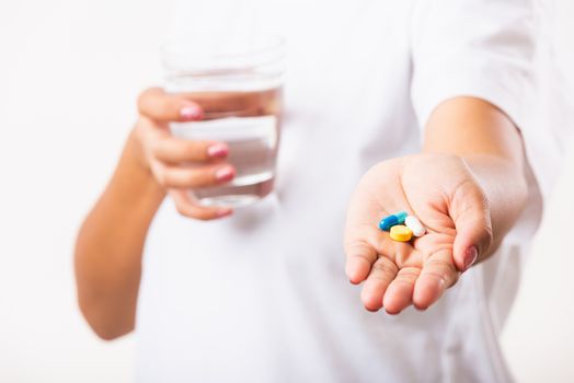 Closeup young Asian woman hold pill drugs in hand ready take medicines with a glass of water, studio shot isolated on white background, Healthcare and medical pharmacy concept