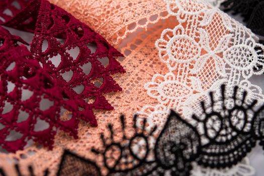 pile of orange, red, white. and black gentle luxury quality guipure, lace fabric. use for sew clothes linen decoration. texture for websites. Space for text.
