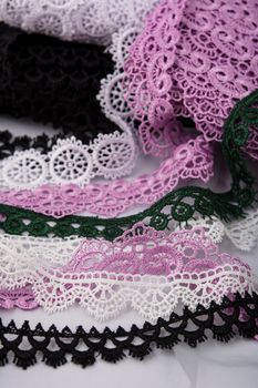 pile of purple, green, white and black gentle luxury quality guipure, lace fabric. use for sew clothes linen decoration. texture for websites. Space for text.