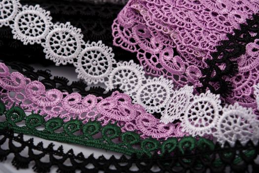 pile of purple, green, white and black gentle luxury quality guipure, lace fabric. use for sew clothes linen decoration. texture for websites. Space for text.