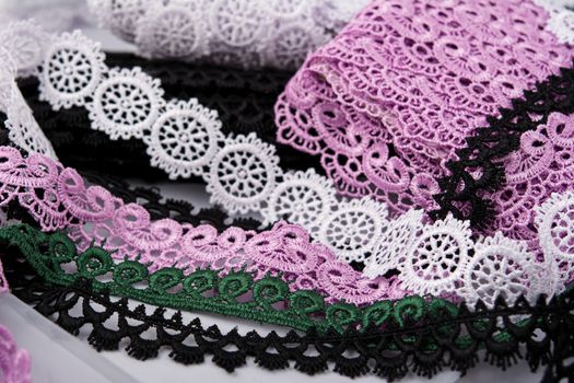 pile of purple, green, white and black gentle luxury quality guipure, lace fabric. use for sew clothes linen decoration. texture for websites. Space for text.