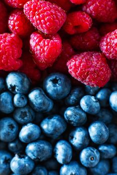 A close-up of raspberries and black blueberry split the frame. Summer vitamins.