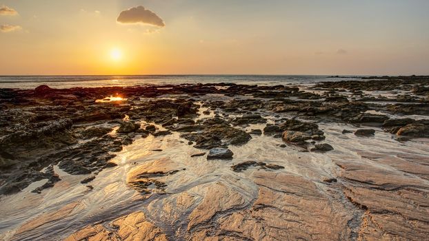 Beach in golden sunset light during low tide showing sand formations and rocks not covered by the sea. Kantiang Bay, Ko Lanta, Thailand.