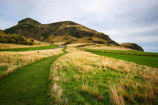 Holyrood Park, green and yellow grass with Arthur's Seat in the background on overcast autumn day. Edinburgh, Scotland