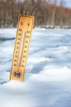 Wooden thermometer standing in snow outside on cold day, illustrating weather with temperature as low as -10 degrees Celsius.