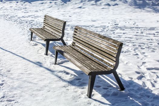 Two empty benches on snow covered ground