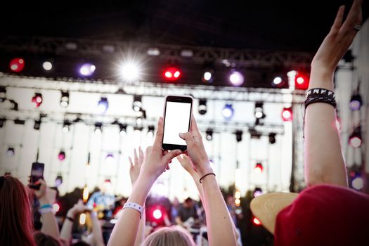 Using smartphone at music show. Empty blank white screen for your image