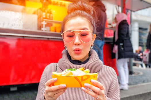 Young Woman Eating A  French Fries Street food in Germany