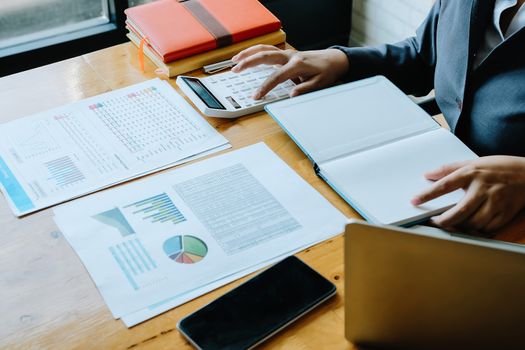 Business woman using calculator for do math finance on wooden desk in office and business working background, tax, accounting, statistics and analytic research concept.