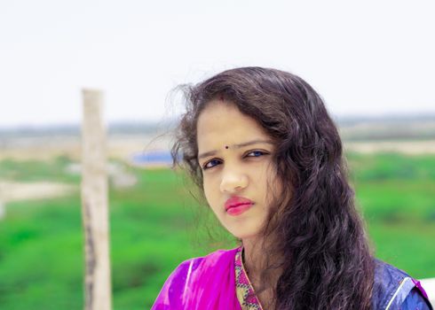 Head shot Portrait of happy Rajasthani young girl with red lipstick on gorgeous lips looking at camera.Side view of young hindu Asian woman with black hairs standing at home in sunny day , portrait