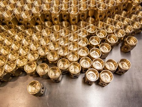 Shiny yellow metal parts background. An abstract industrial close-up background of shiny brass metal threaded hexagonal parts after turning and machining.