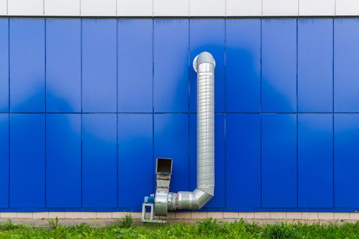 industrial grade air extraction duct with electrical motor on blue wall.