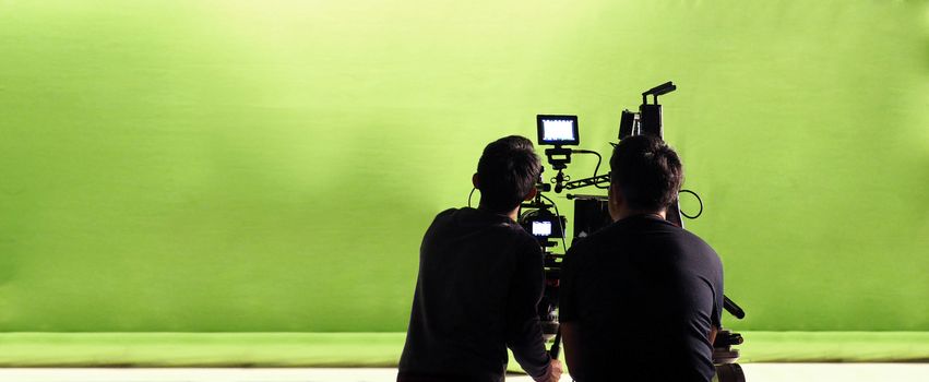 Camera and green screen studio in panorama view and man working or shooting or recording or filming.