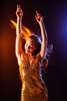 Portrait of dancing girl in golden dress on disco party blue and red studio lights