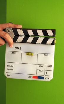 Movie slate board or clapper board and man hand and white color and green screen background in studio.