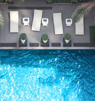 Swimming pool blue water in summer and white beach beds and top view angle.