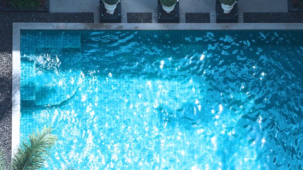 Swimming pool blue water in summer and white beach beds and top view angle.