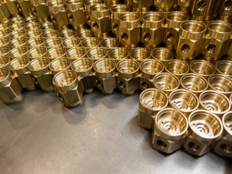 Shiny yellow metal parts background. An abstract industrial close-up background of shiny brass metal threaded hexagonal parts after turning and machining.