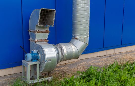 industrial grade air extraction duct with electrical motor on blue wall.