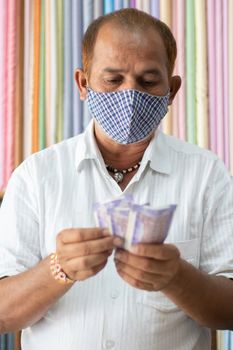 Small business owner in medical mask Counting Money at cloth shop during coronavirus or covid-19 Crisis - Concept of back to business, making money and reopen economy.
