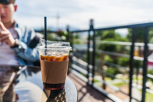 Cup of iced coffee with straw on wooden table