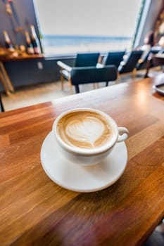 Cup of coffee with latte art on wooden table