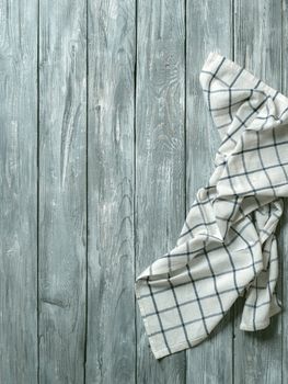 Gray wooden table with linen kitchen towel or textile napkin flat lay. Blue tablecloth on old gray wood tabletop. Copy space for text. Can use as mock up for design. Vertical.