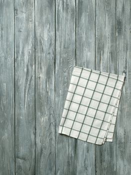 Gray wooden table with linen kitchen towel or textile napkin flat lay. Blue tablecloth on old gray wood tabletop. Copy space for text. Can use as mock up for design. Vertical.