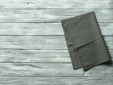 Gray wooden table with balck and white dark linen kitchen towel or textile napkin flat lay. Dark tablecloth on old gray wood tabletop. Copy space for text. Can use as mock up for design.