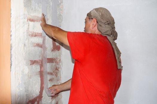 a man gluing a reinforcing tape to a crack in a wall.