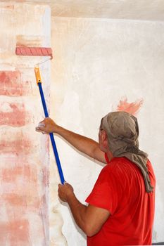 a man with a paint roller applies a primer to the wall.