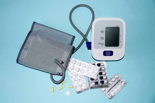 tonometer and pills on blue background, view from above