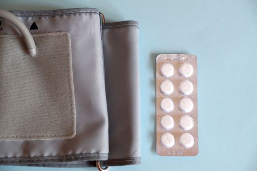 tonometer and pills on blue background, view from above