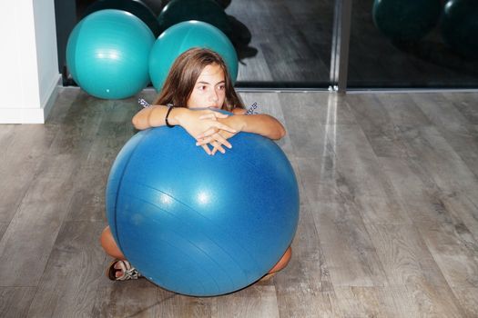 teenager girl with fitness ball in gym.