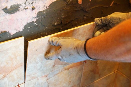 a man laying ceramic tiles on the wall close up