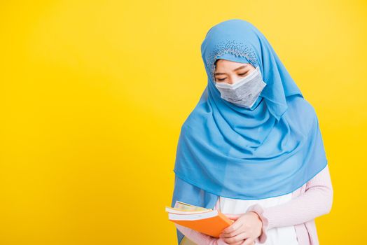 Asian Muslim Arab, Portrait of young woman religious wear veil hijab and face mask protective to prevent coronavirus she student hold books on hand, isolated on yellow background, Back to college