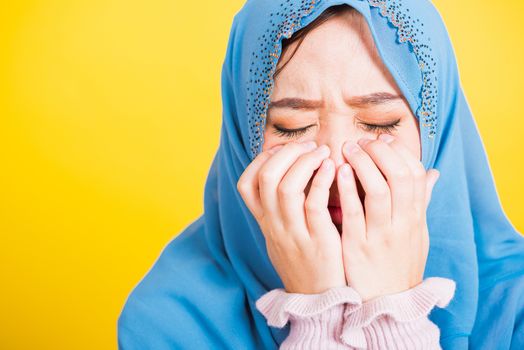 Asian Muslim Arab, Portrait of happy beautiful young woman religious wear veil hijab she sad crying using hand wiping tears in her eyes, studio shot isolated on yellow background with copy space